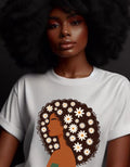 May include: A white t-shirt with a brown and white illustration of a woman with curly hair decorated with white flowers.